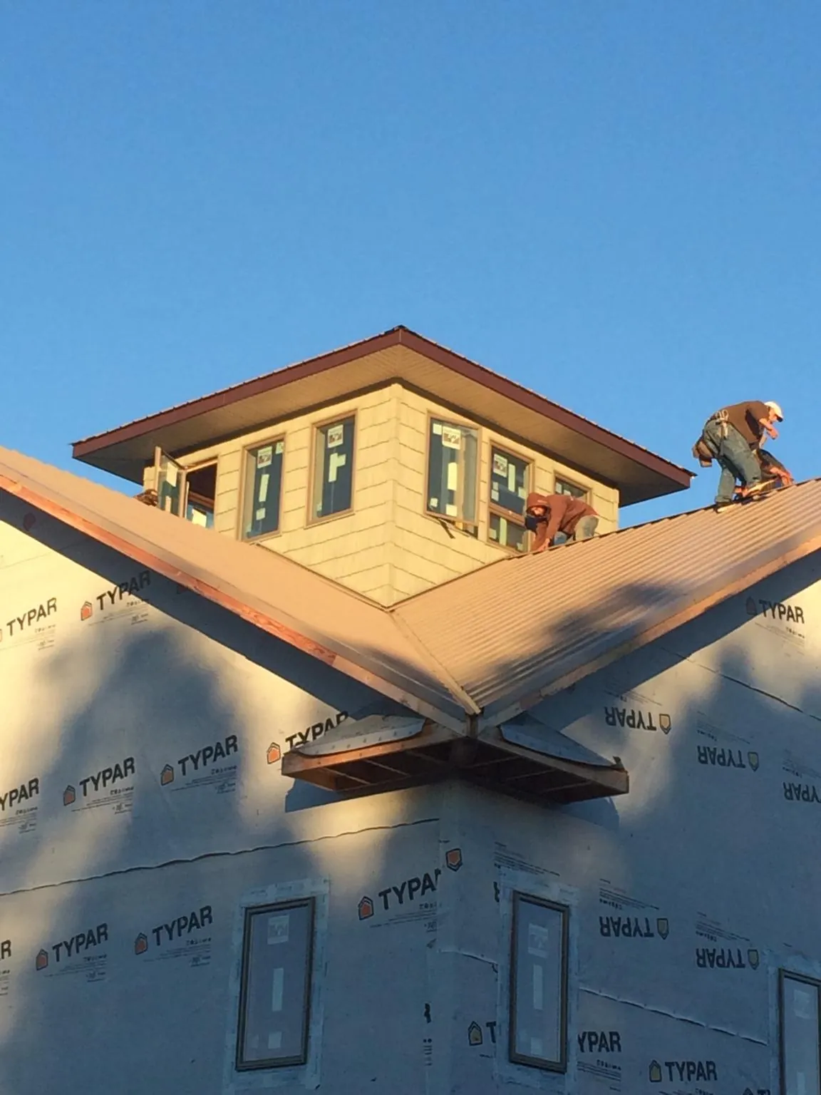 Roofers working around a rooftop cupola on a new metal roof at sunset — Roof Waterproofing in Medina by Roofing Brothers